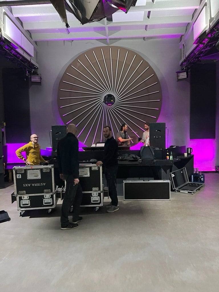 The ARTFÊTE crew building the stage — flight cases, lighting and DJ setup in the raw hall before the night