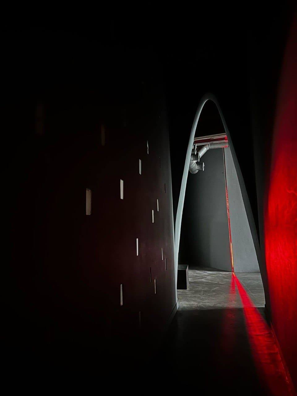 Dark arched passage with a single red light line during an ARTFÊTE night