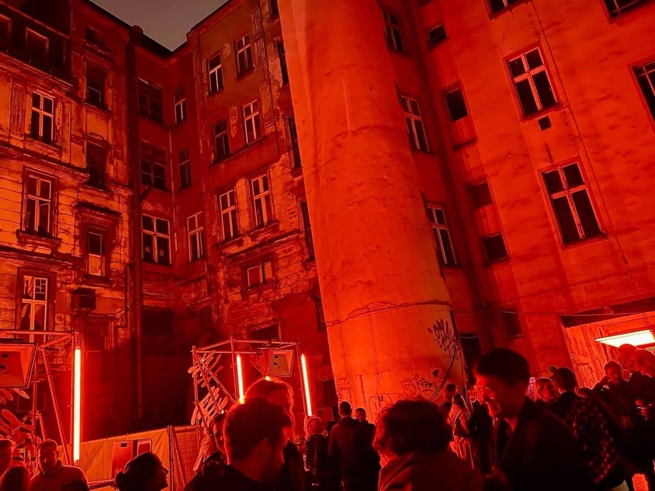 Historic courtyard fully immersed in red light with guests and light objects