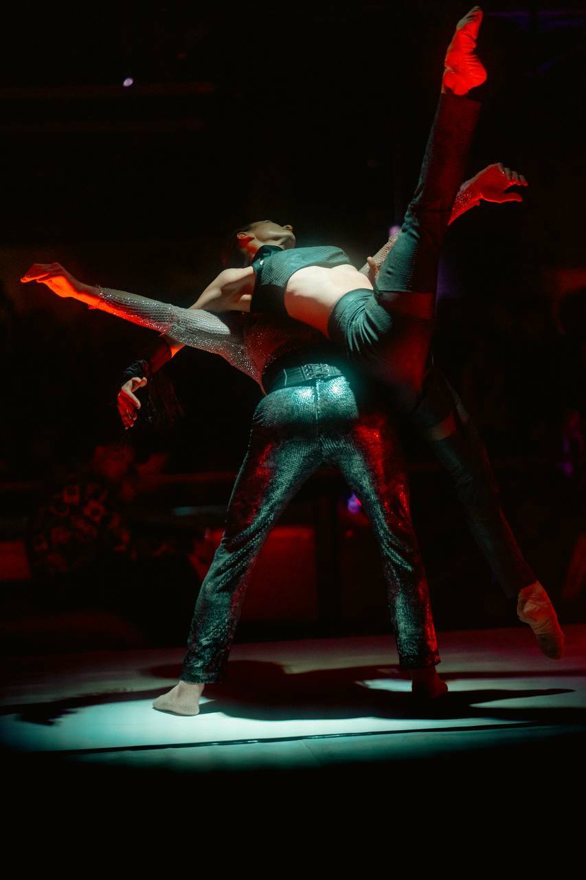 An acrobatic duo mid-lift on the lit stage