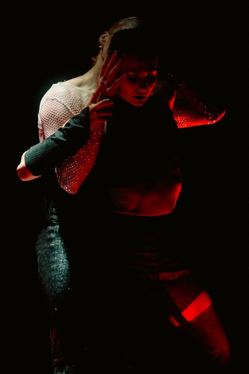 Two dancers in an intimate moment under red light