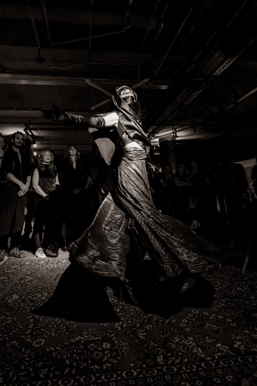 A dancer in a flowing gold dress before the guests in the raw venue